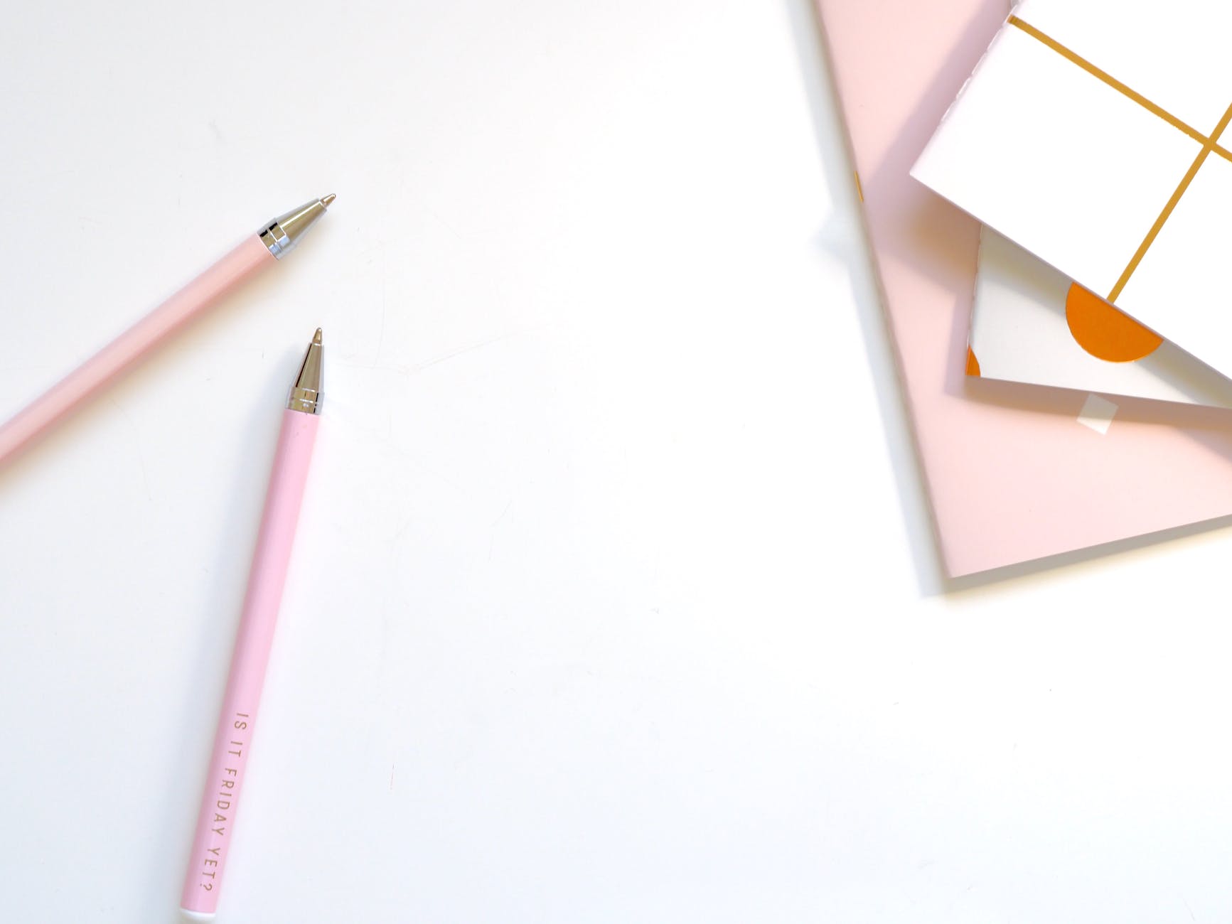 Image of notebook and pens on a light pink background.